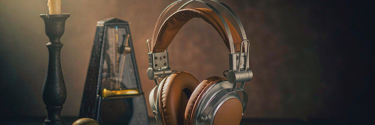 Vintage headphones beside a candle and brass metronome on a dark wooden table