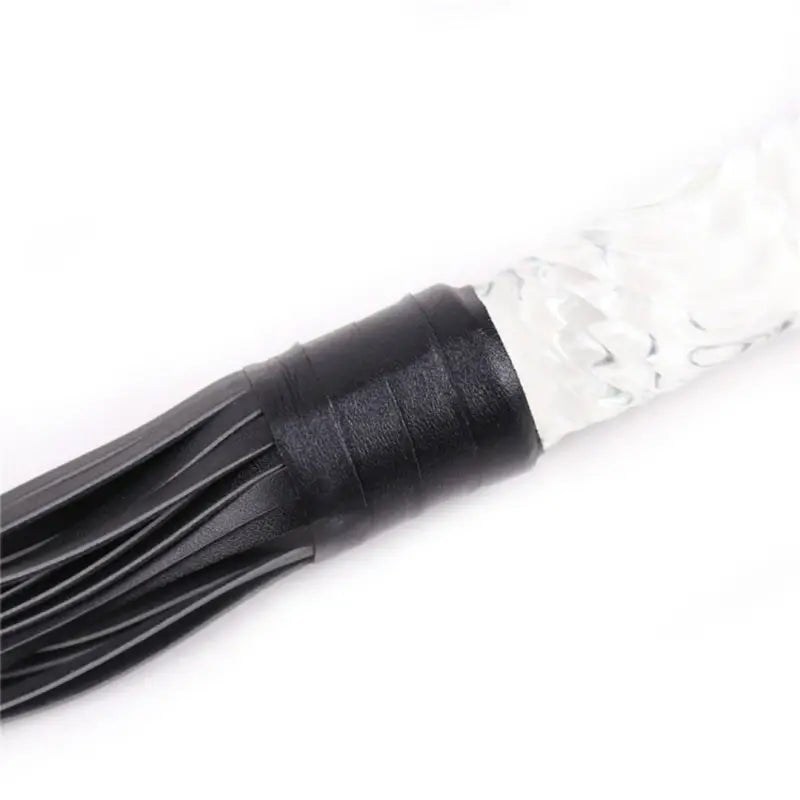 Close-up of Dominitoy leather flogger tail base and textured glass handle