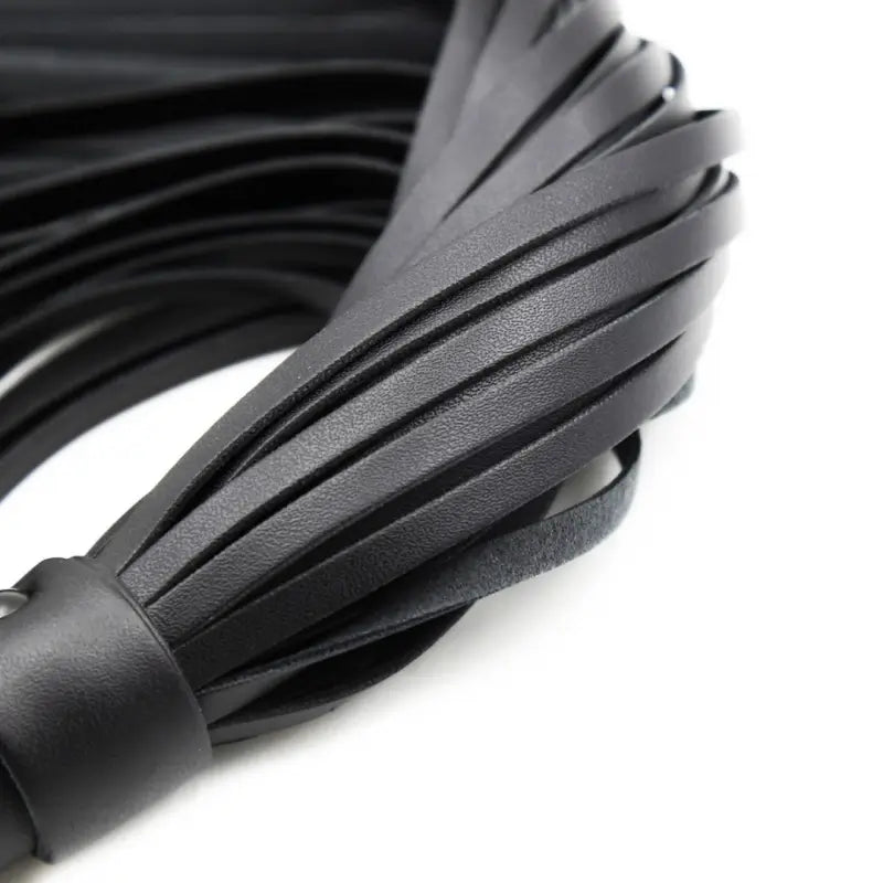 Close-up of Dominitoy black PU leather flogger tails

