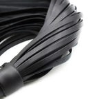 Close-up of Dominitoy black PU leather flogger tails
