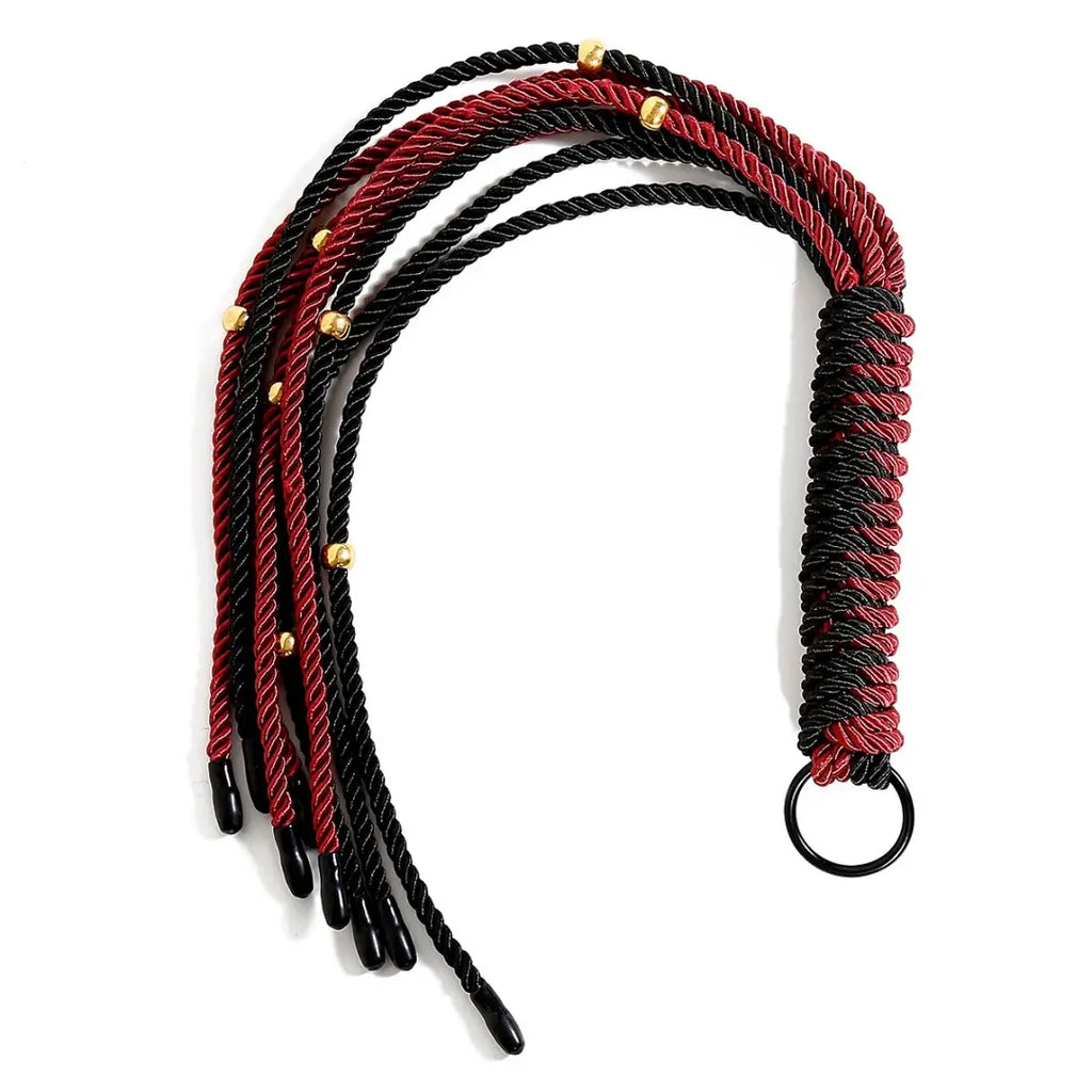 Dominitoy red and black braided rope flogger laid on white background